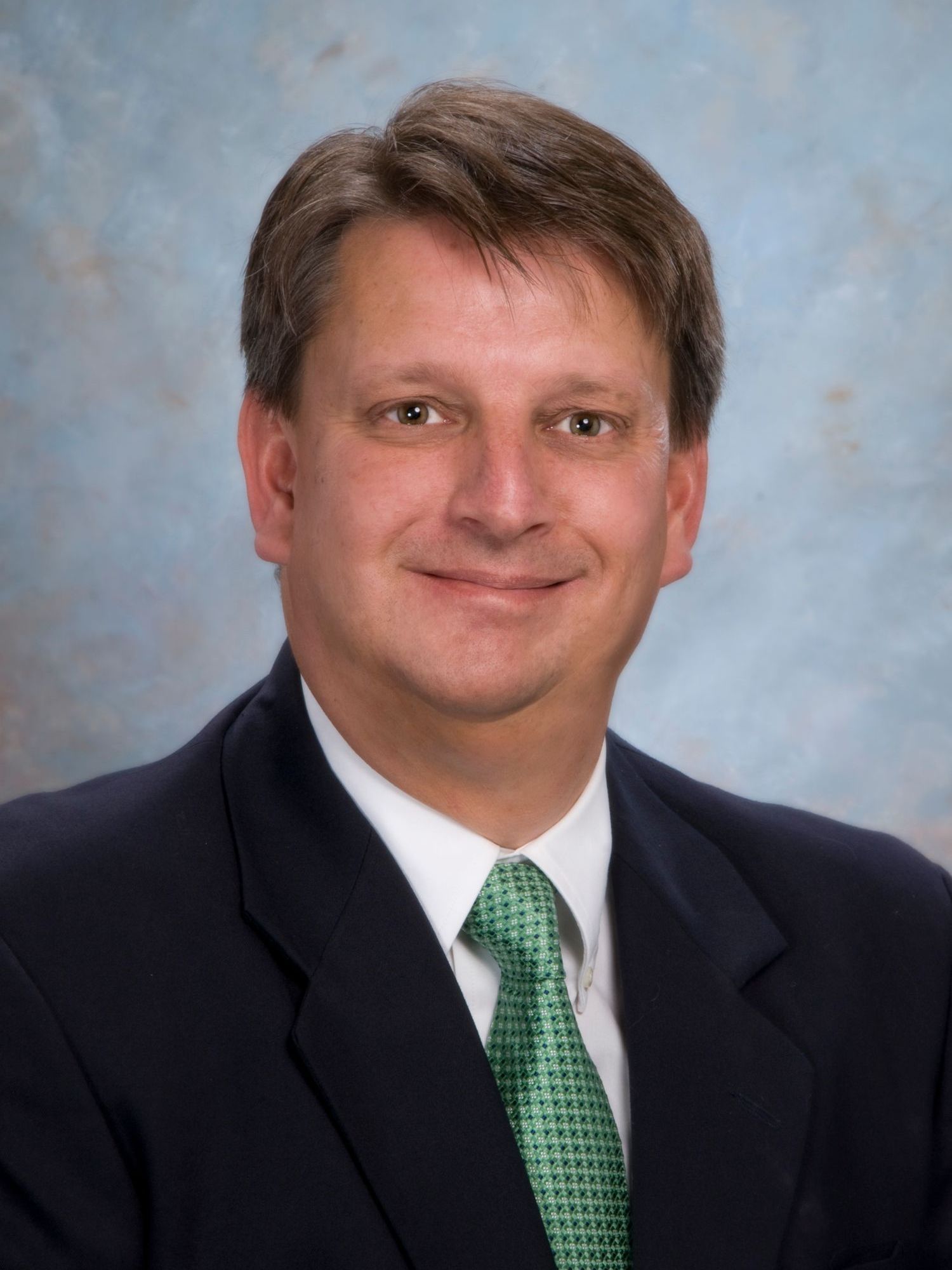 A man in a suit and tie is smiling for the camera