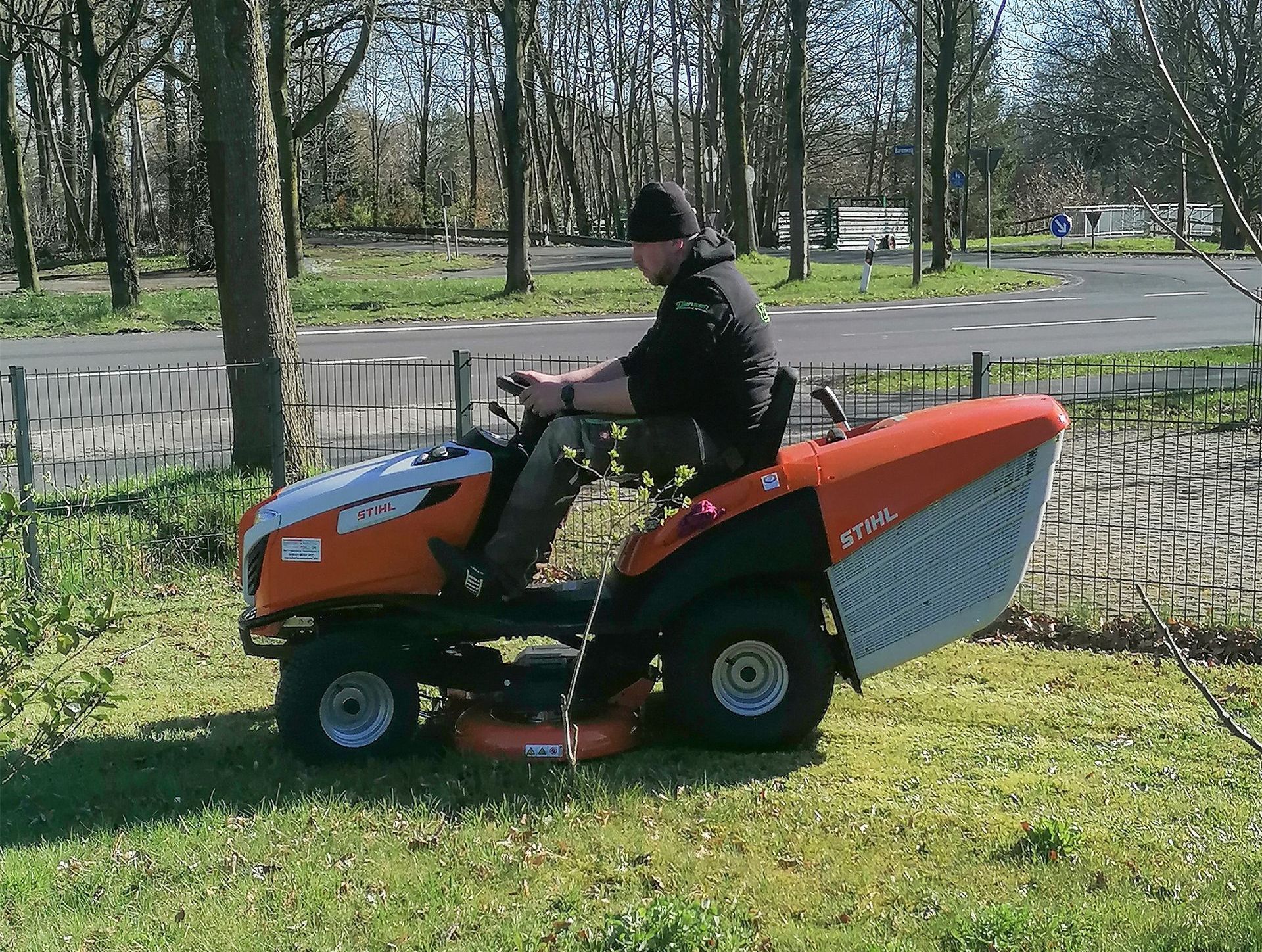 Ein Mann fährt mit einem Rasenmäher in einem Park