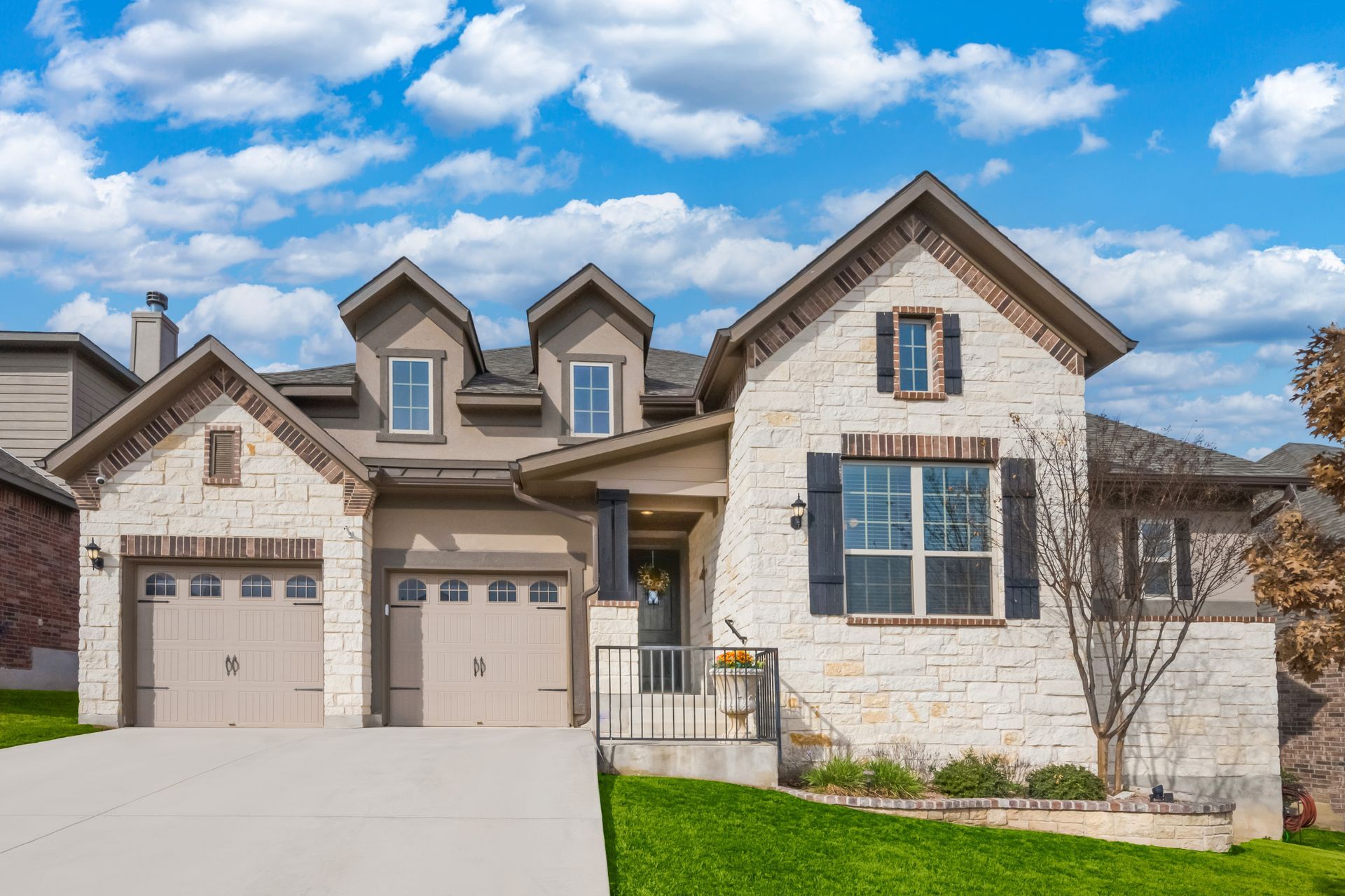 A large brick house with two garages and a driveway in front of it.