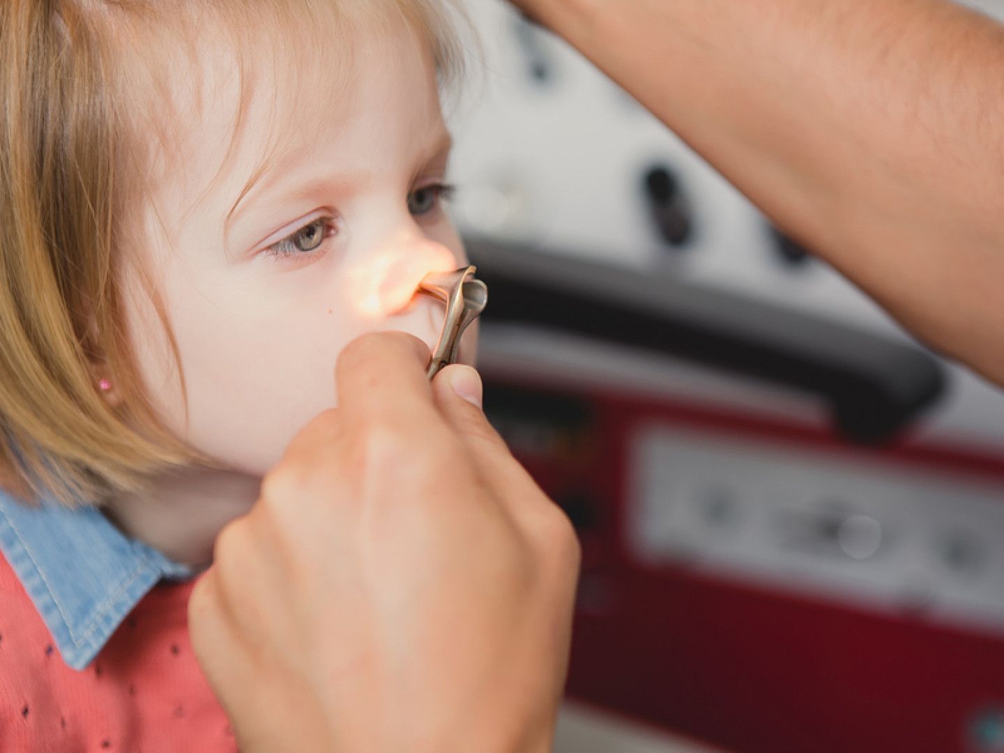 Hand removing a tissue from a child’s nose in a close-up indoor scene