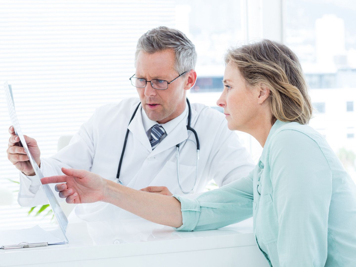 Doctor discussing chart with patient in a bright clinic office