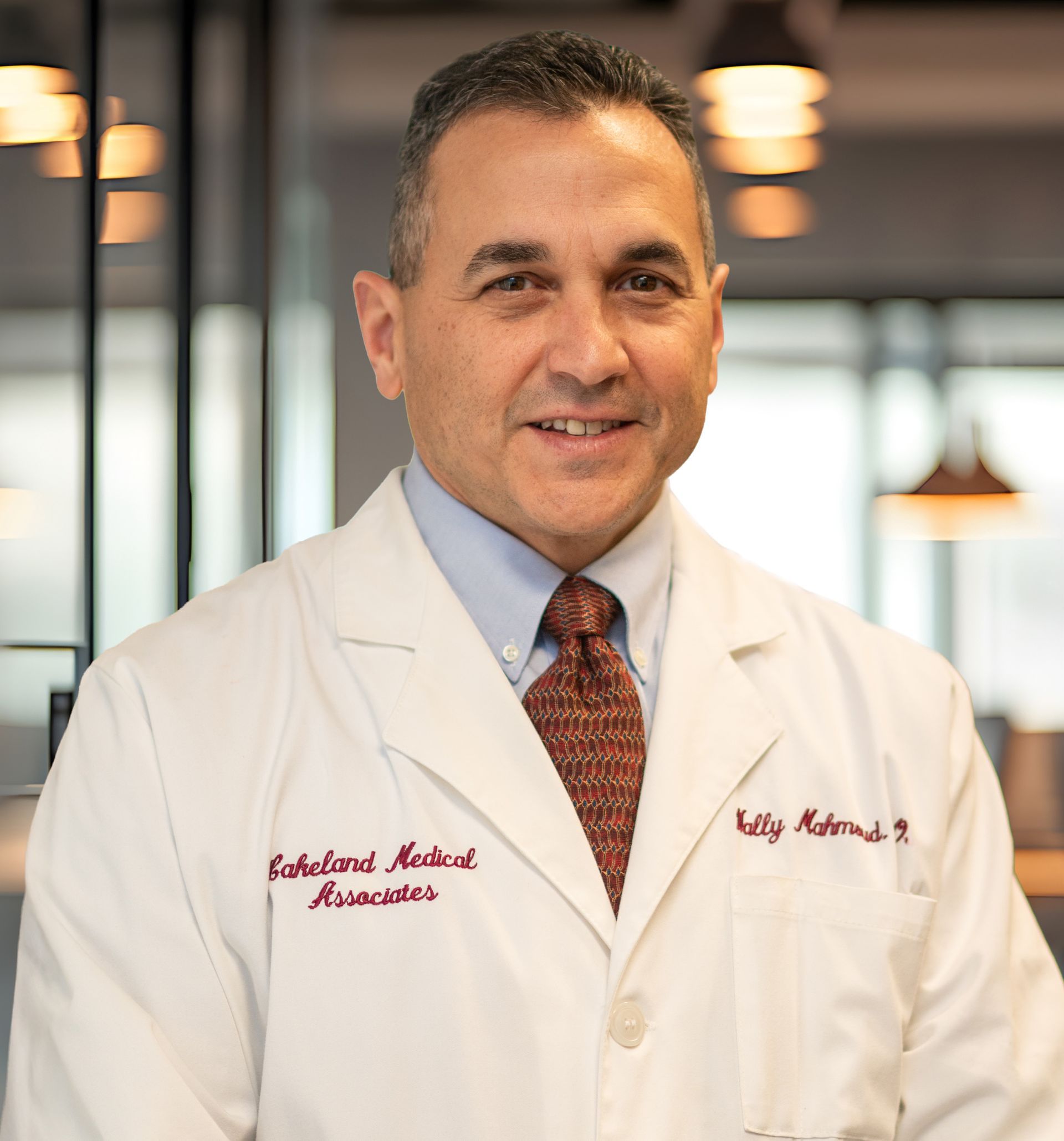 Portrait of a doctor in a white coat standing in a modern office, smiling at the camera