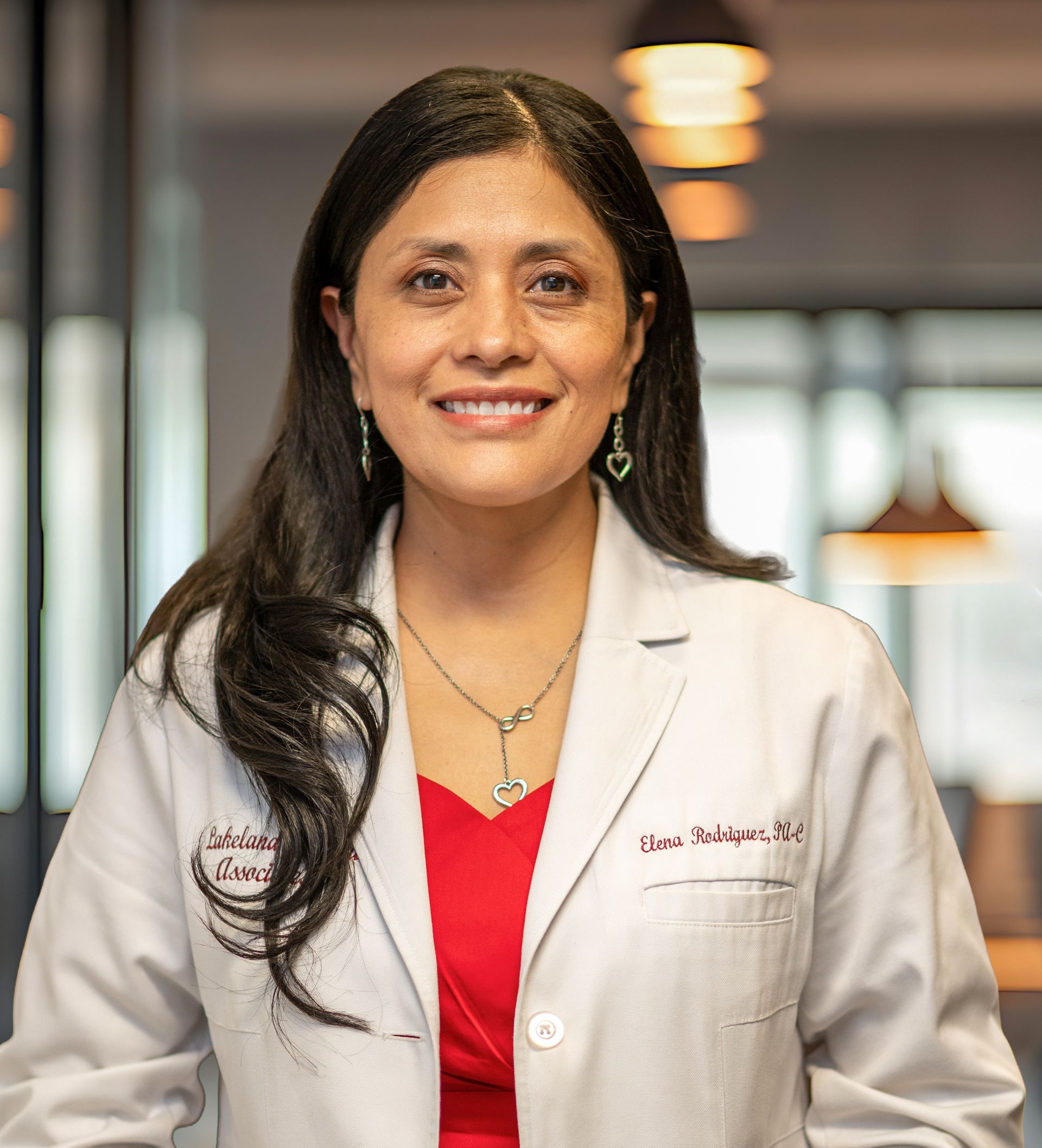 Smiling doctor in a white coat standing in a softly lit hospital hallway