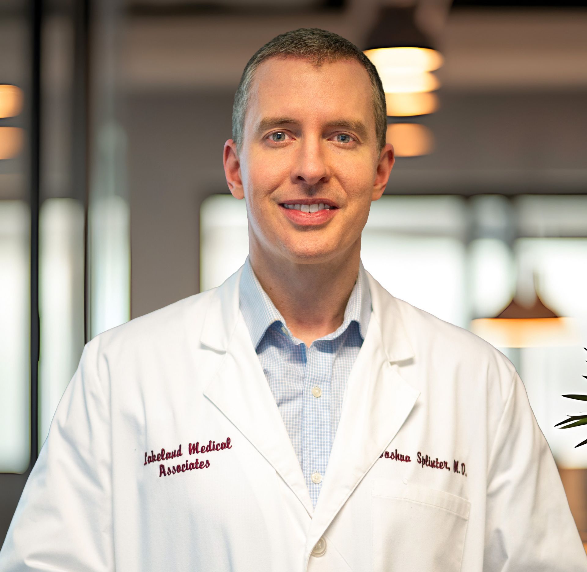 Smiling doctor in a white lab coat standing in a modern office interior
