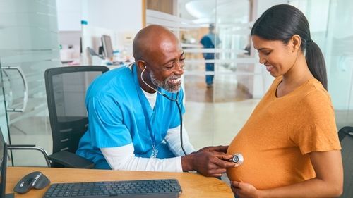 Healthcare worker checking a pregnant patient’s vital signs in a clinic
