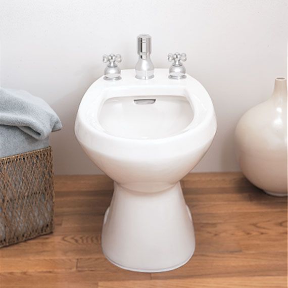 A bidet in a bathroom next to a basket and vases