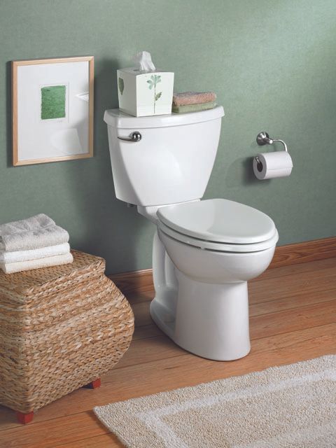 A toilet in a bathroom next to a basket of towels
