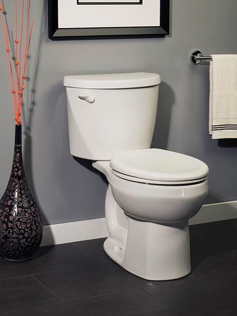 A white toilet in a bathroom next to a vase