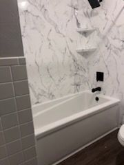 A shower with a sliding glass door and black handles