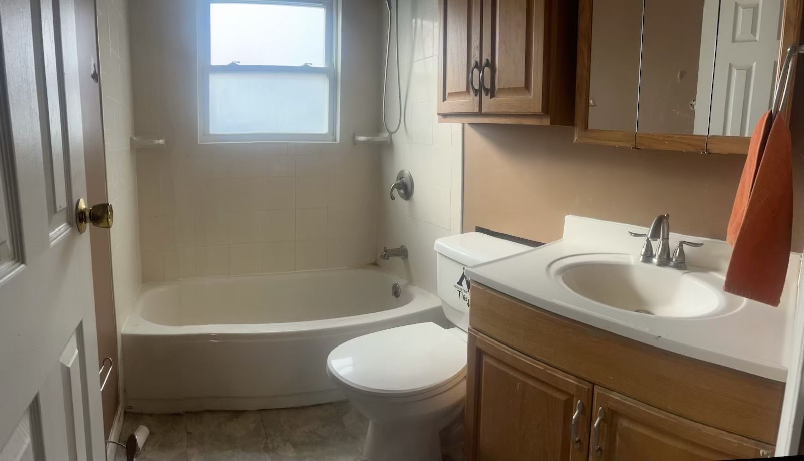 A bathroom with a toilet , tub and mirror.
