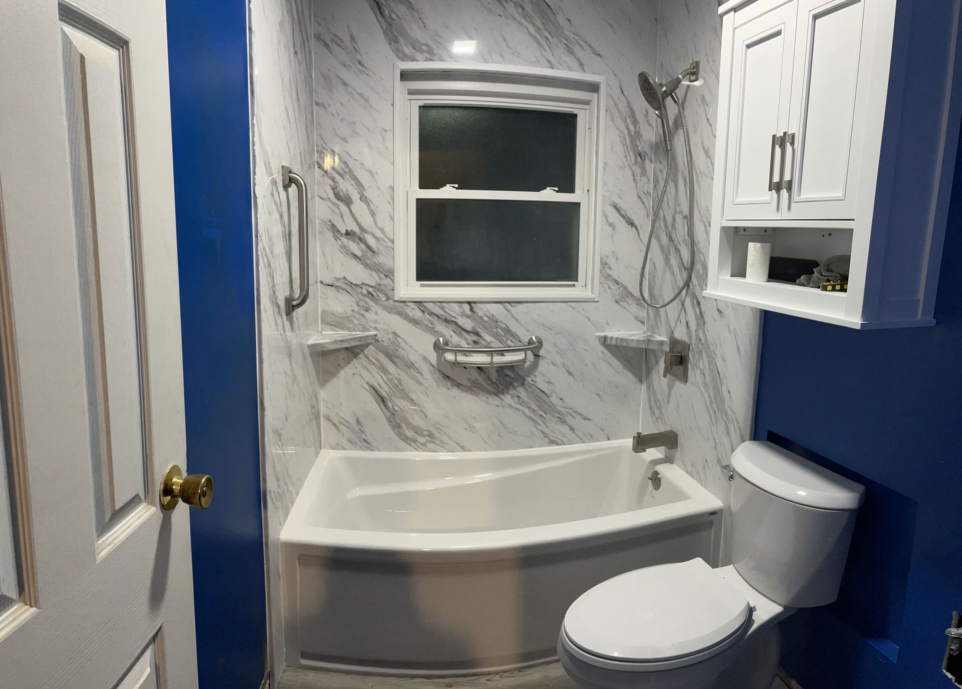 A shower with a sliding glass door and black handles