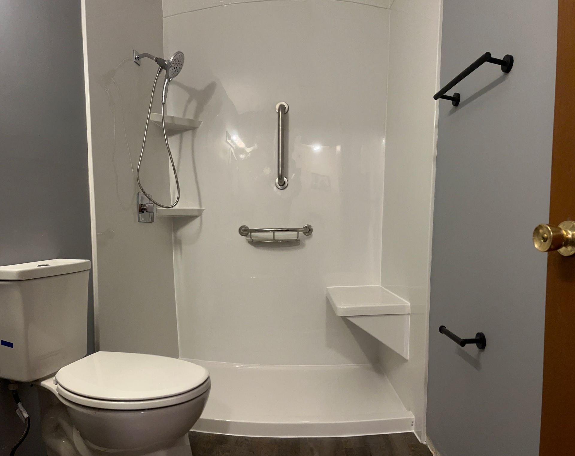 A shower with a sliding glass door and black handles