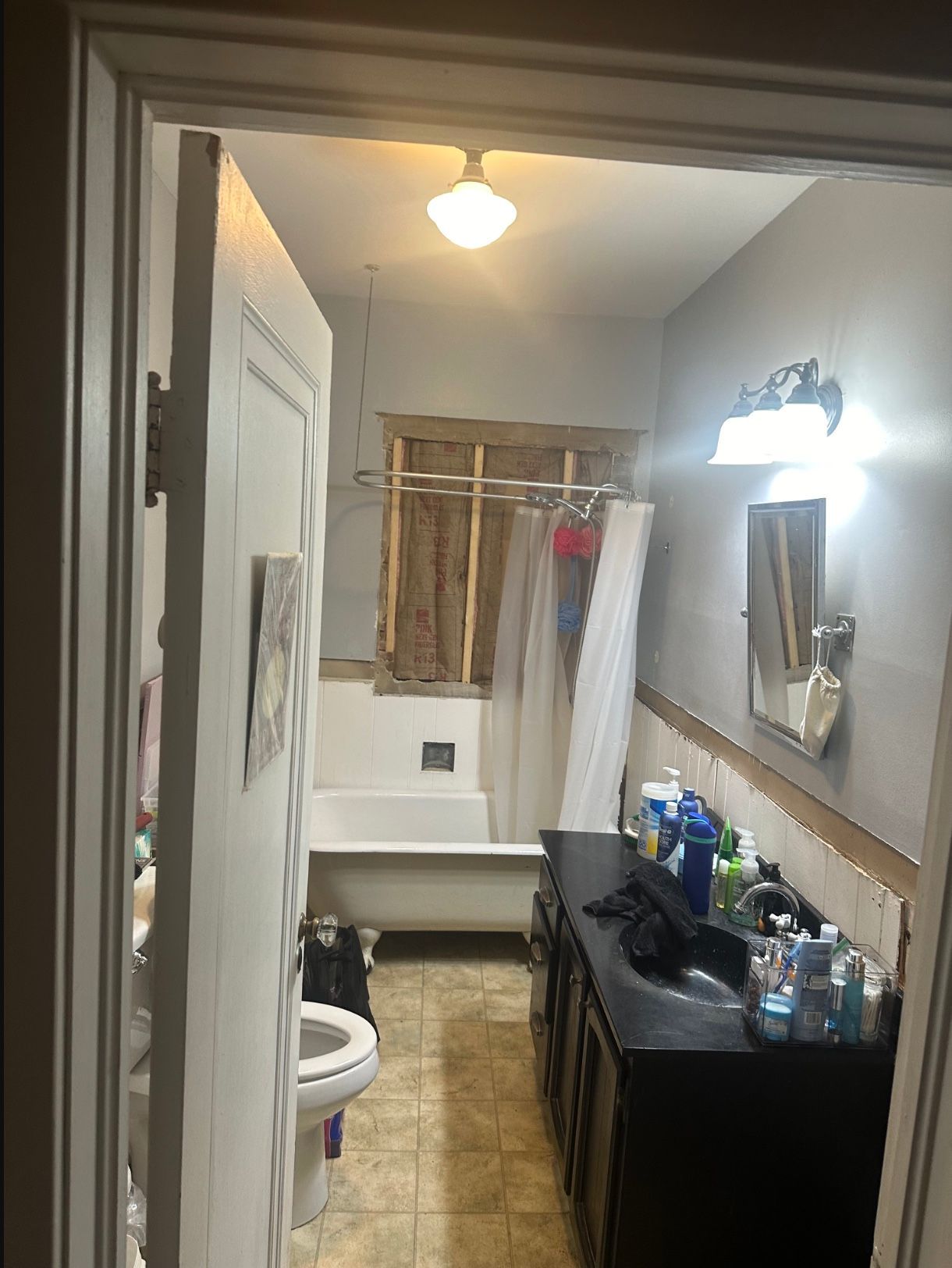 A bathroom with a green towel hanging over the shower door.