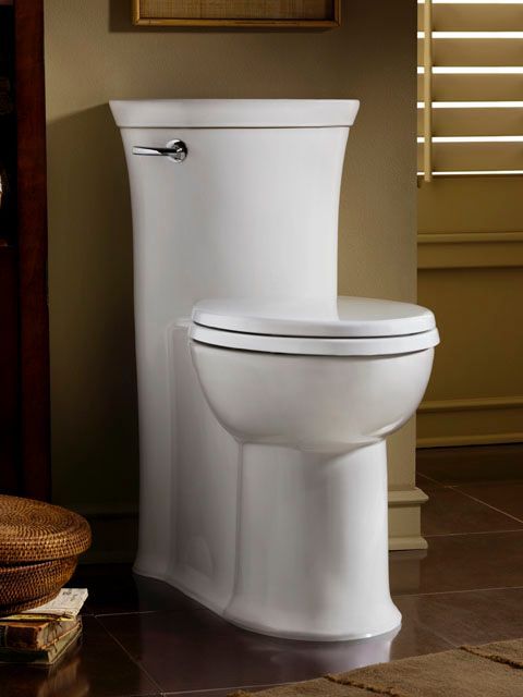 A white toilet in a bathroom next to a window
