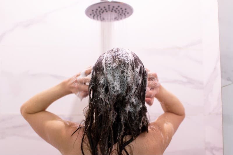 A woman in a black swimsuit is taking a shower.