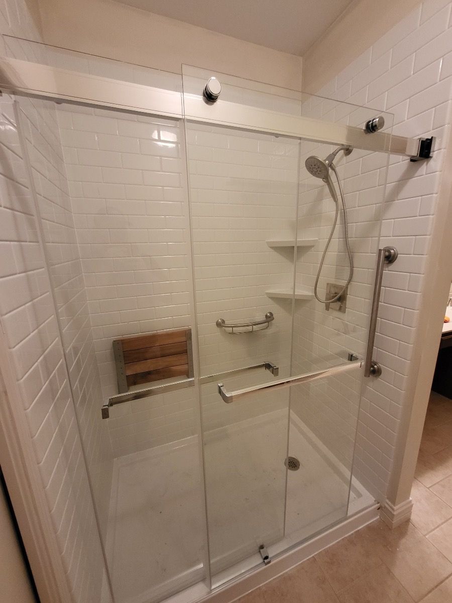 A shower with a sliding glass door and black handles