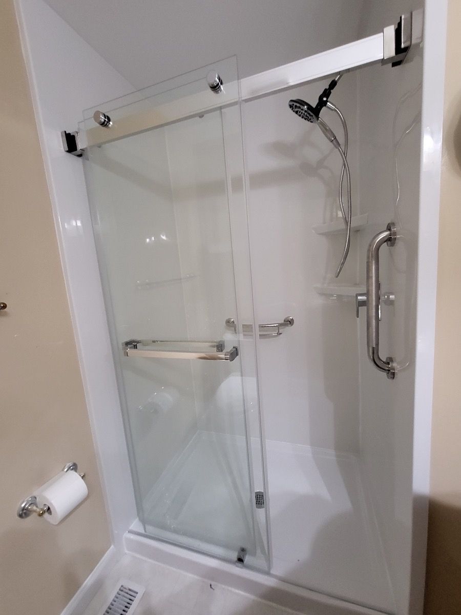 A shower with a sliding glass door and black handles
