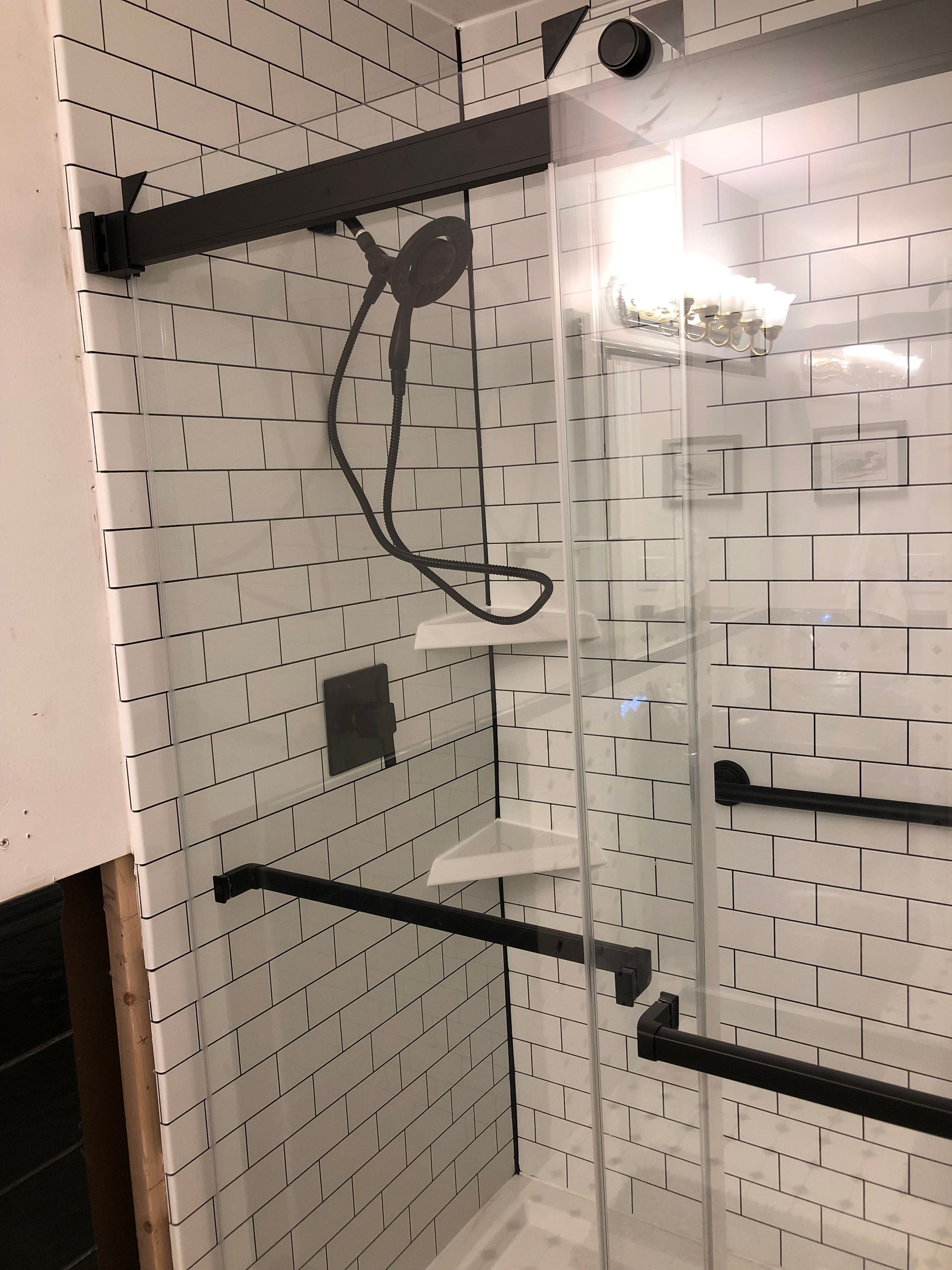 A shower with a sliding glass door and black handles