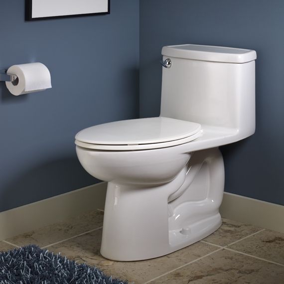 A white toilet in a bathroom next to a paper towel dispenser