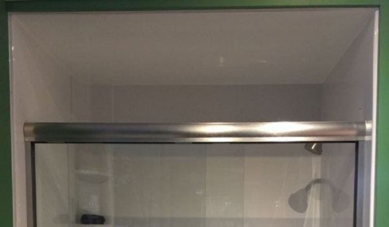 A shower stall with a sliding glass door and a shower head.