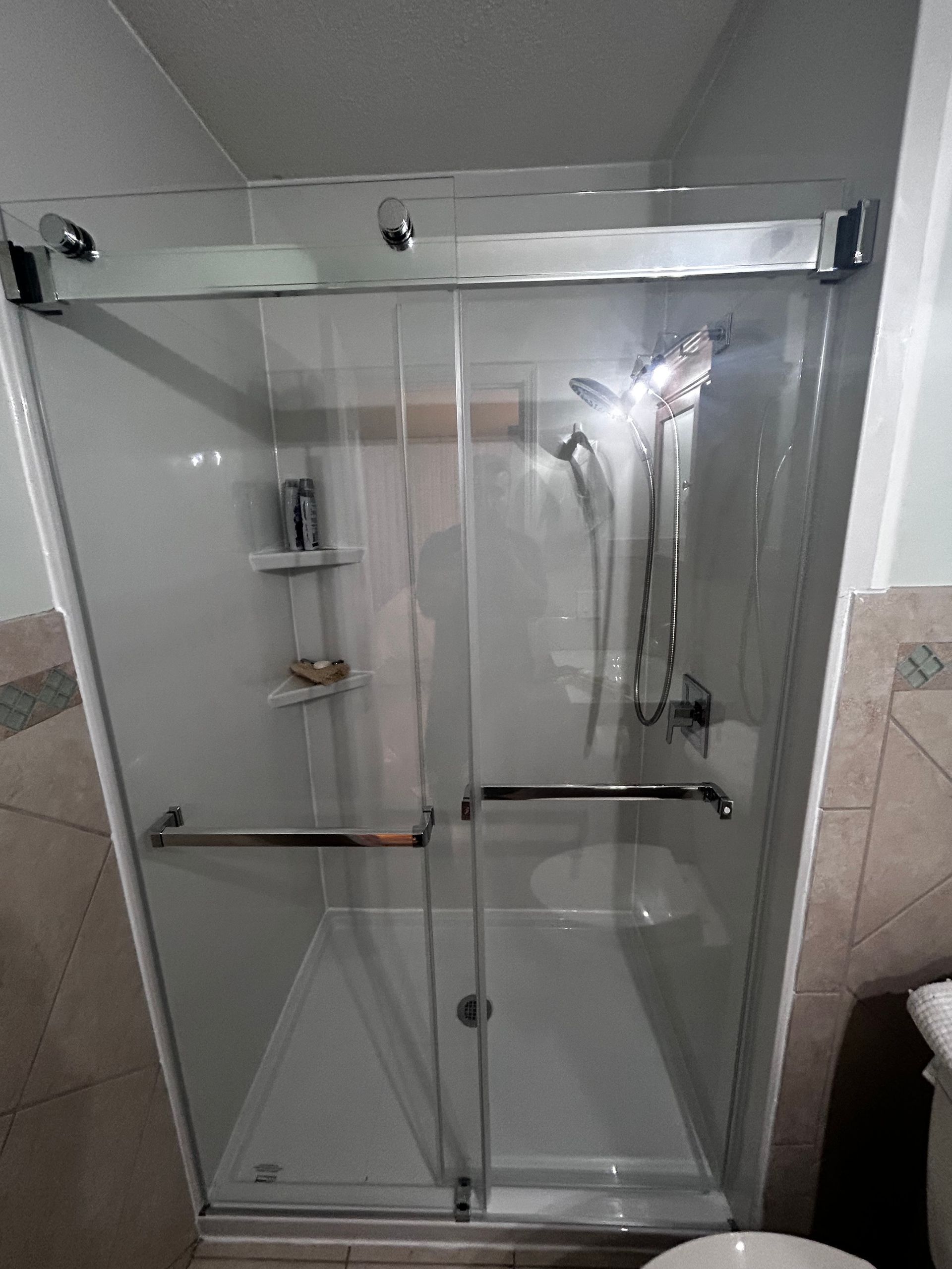 A bathroom with a sliding glass shower door and a toilet.