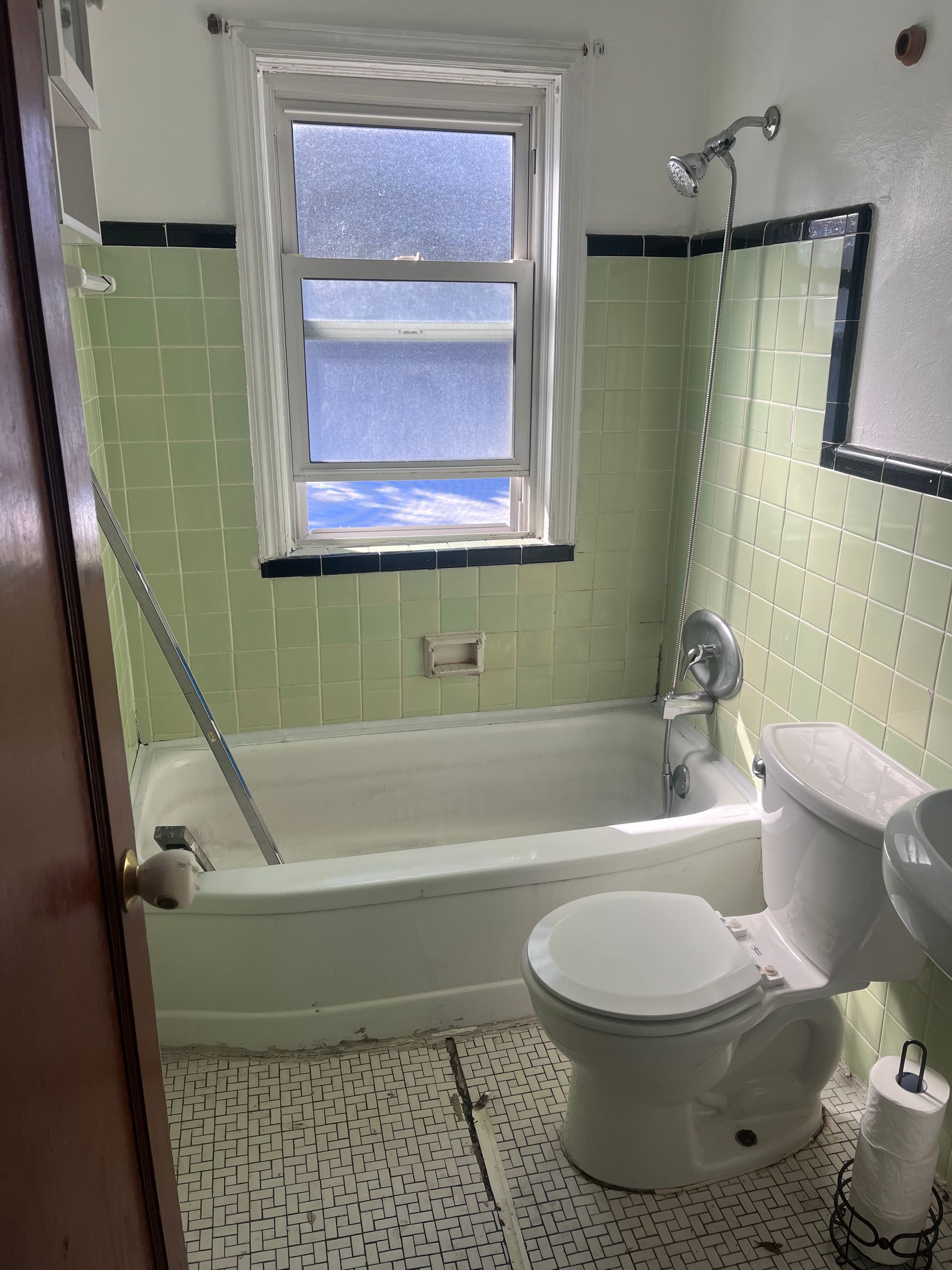 A bathroom with a tub , toilet , sink and window.