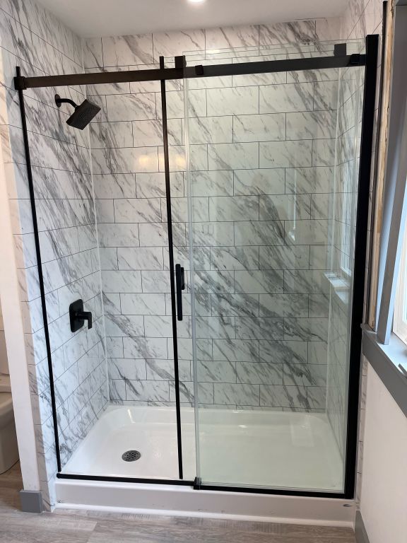 A bathroom with marble tiles and a sliding glass shower door.