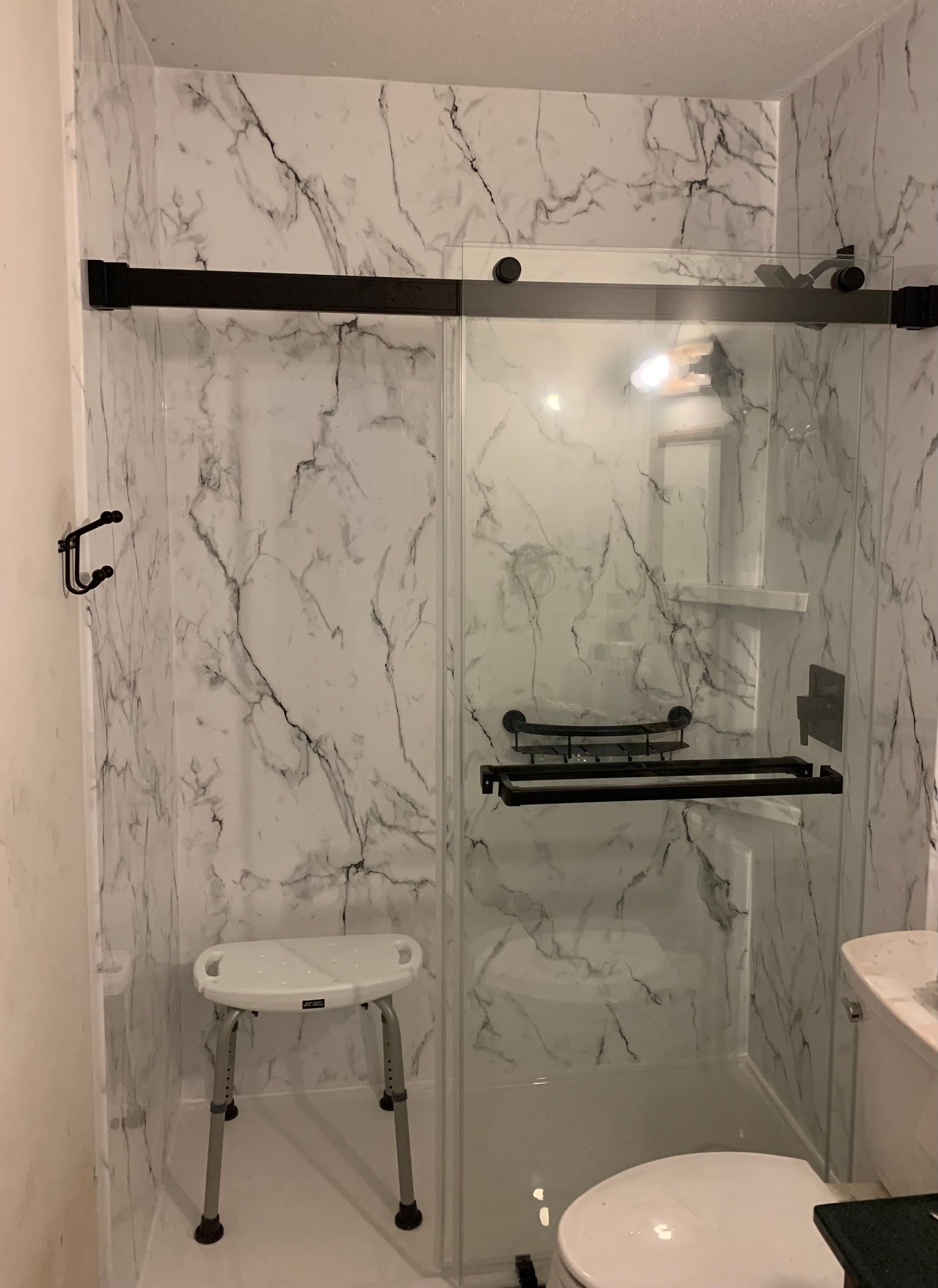 A shower with a sliding glass door and black handles
