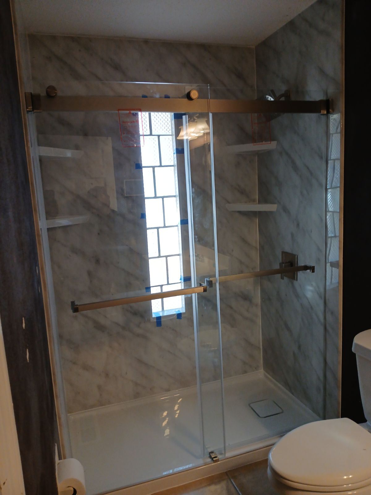 A shower with a sliding glass door and black handles