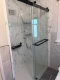 A bathroom with a sliding glass shower door and marble walls.