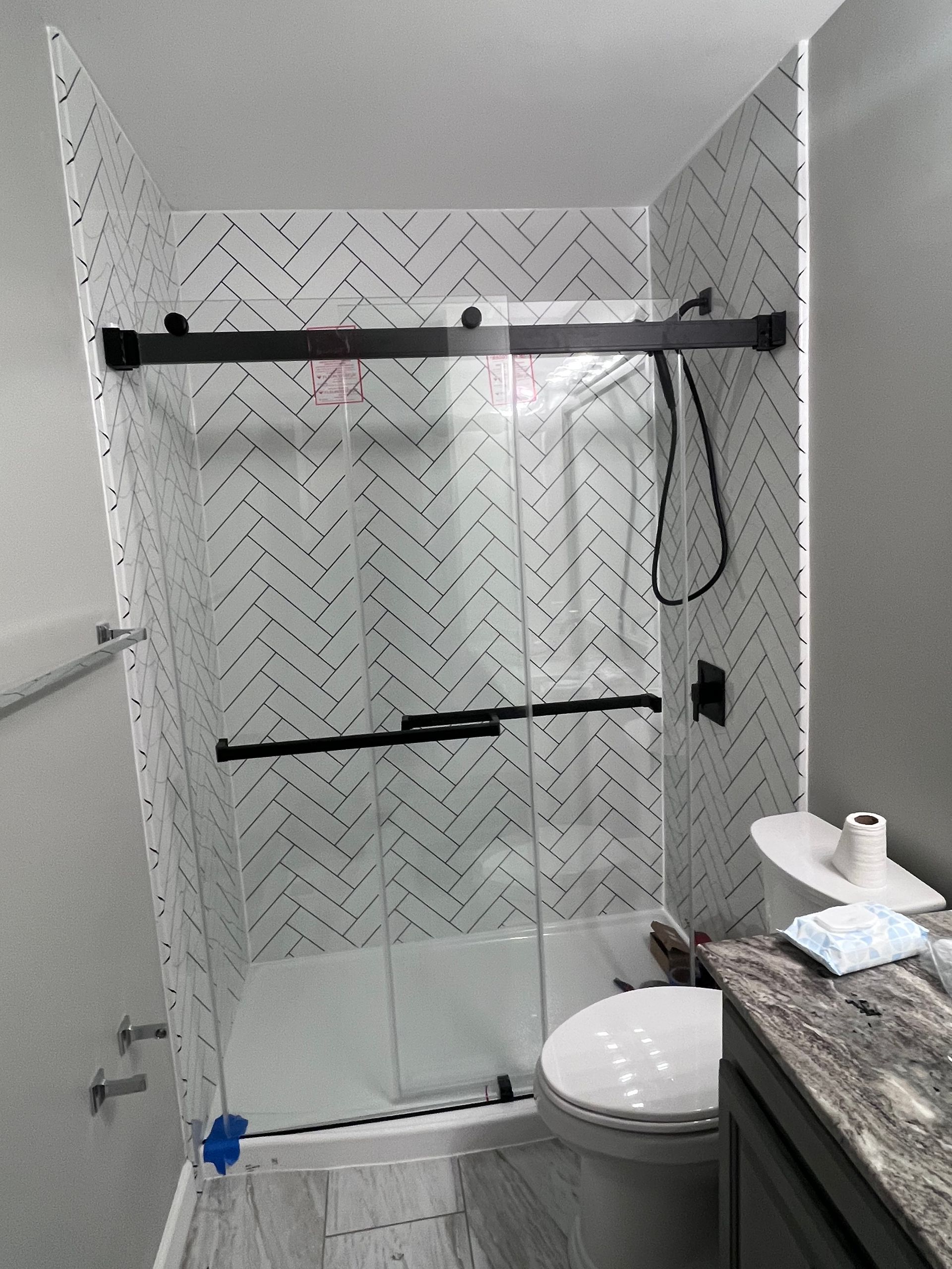 A bathroom with a shower , toilet , sink and mirror.