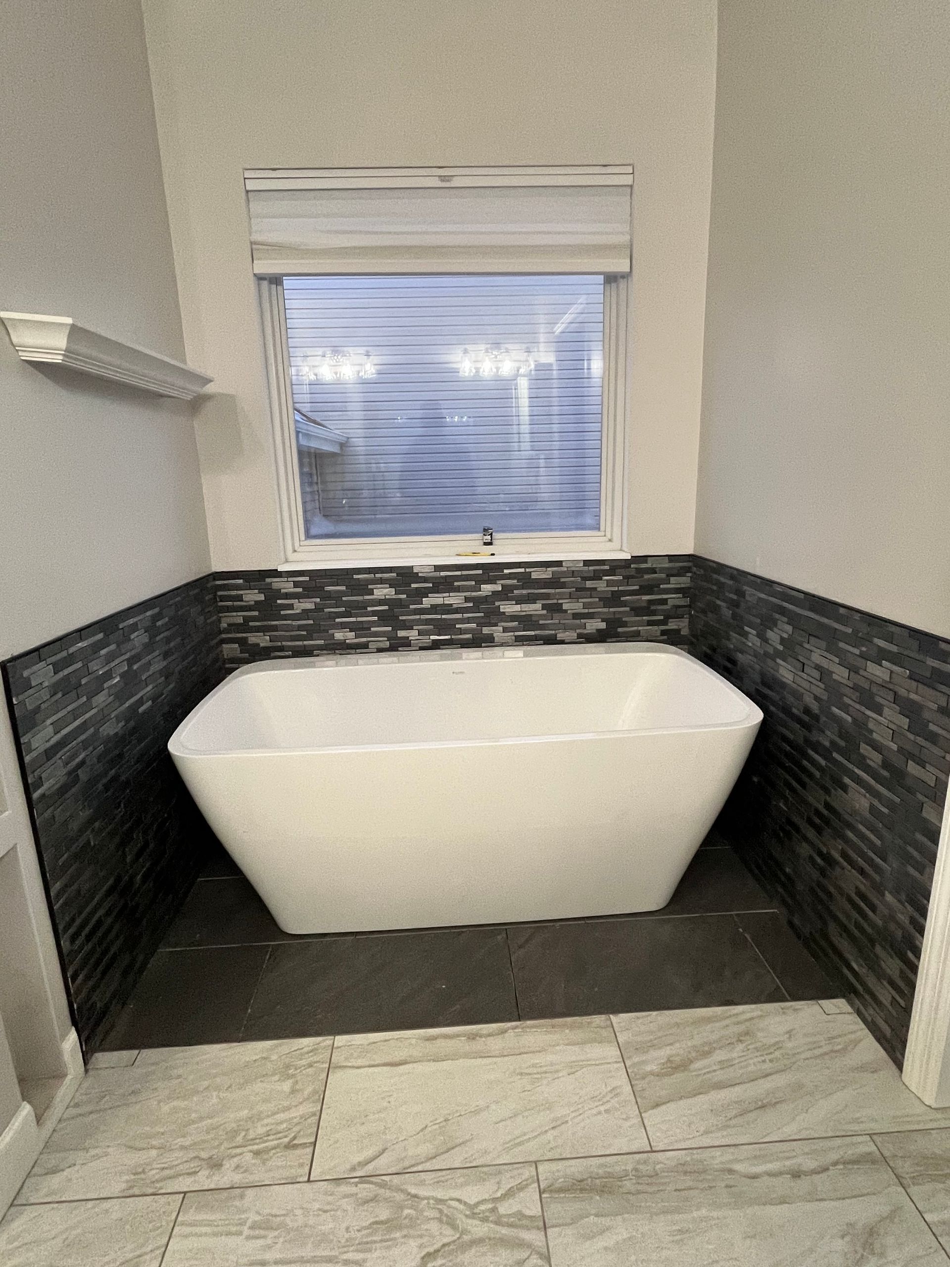 A bathroom with a bathtub and a window.