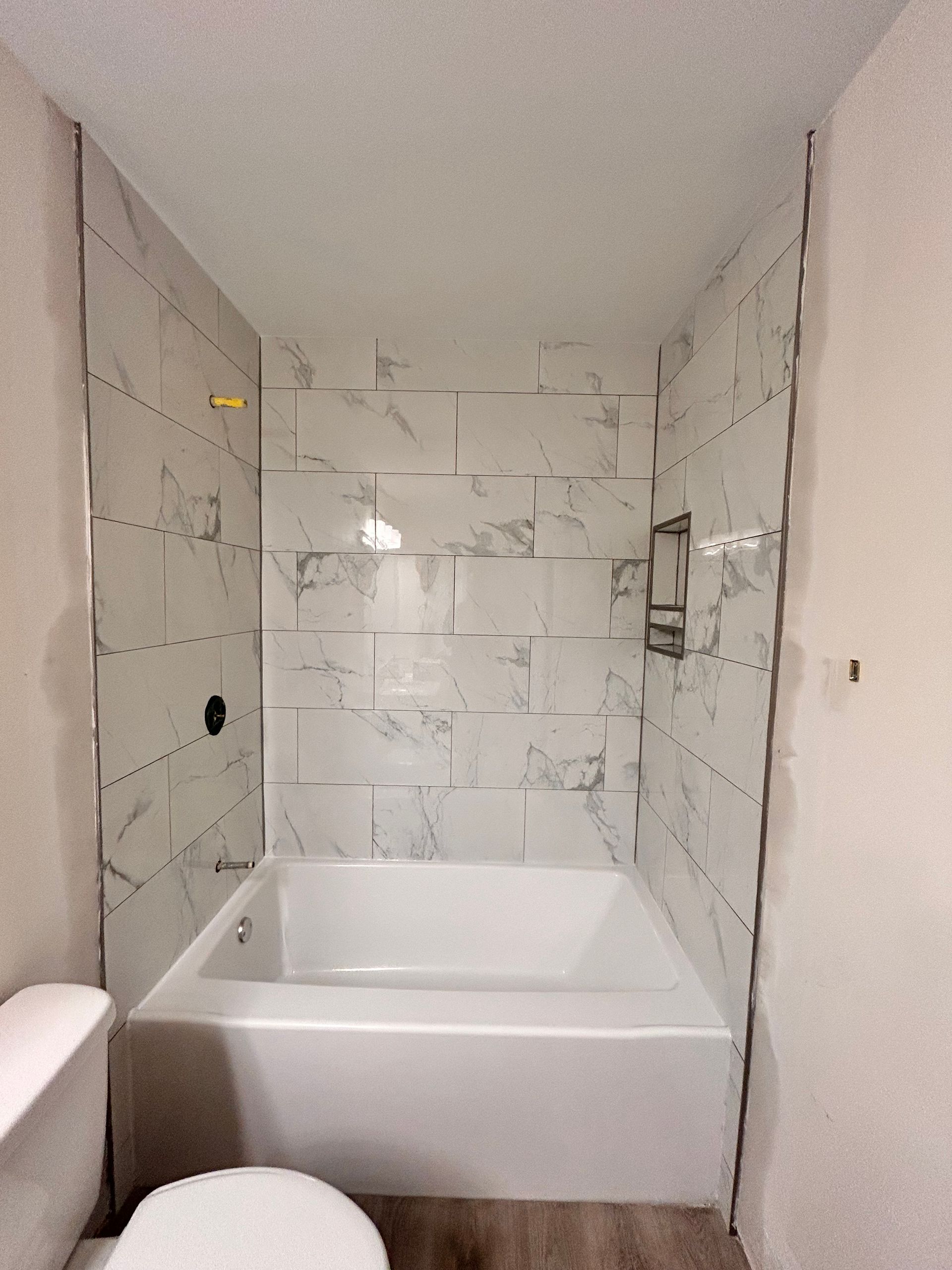 A bathroom with a tub , toilet and shower.