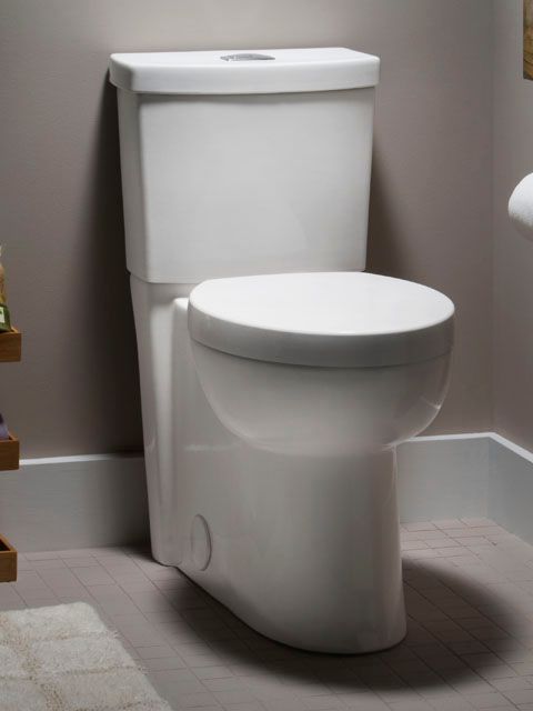A white toilet sits in a bathroom next to a shelf