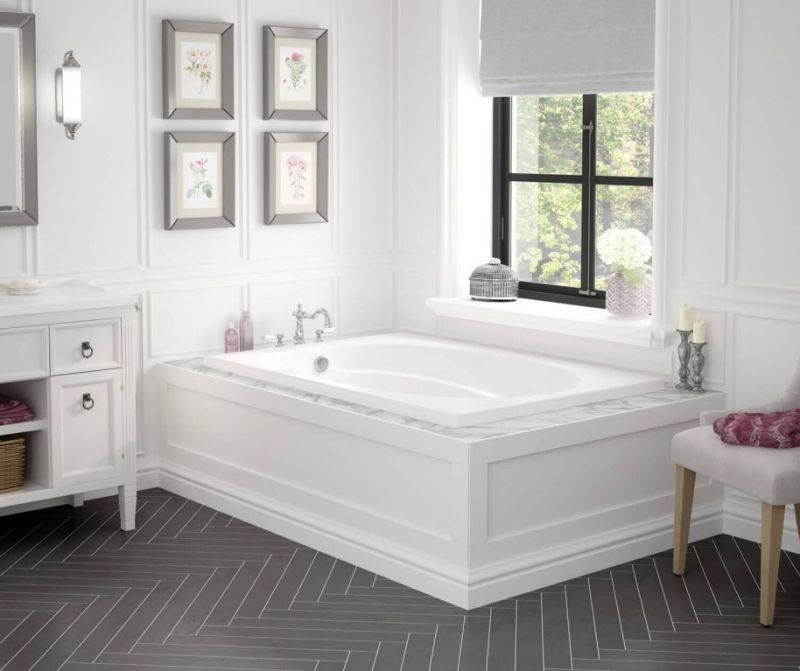 A bathroom with a tub , sink , chair and window.