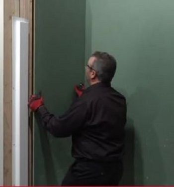 A man in a black shirt and red gloves is opening a door