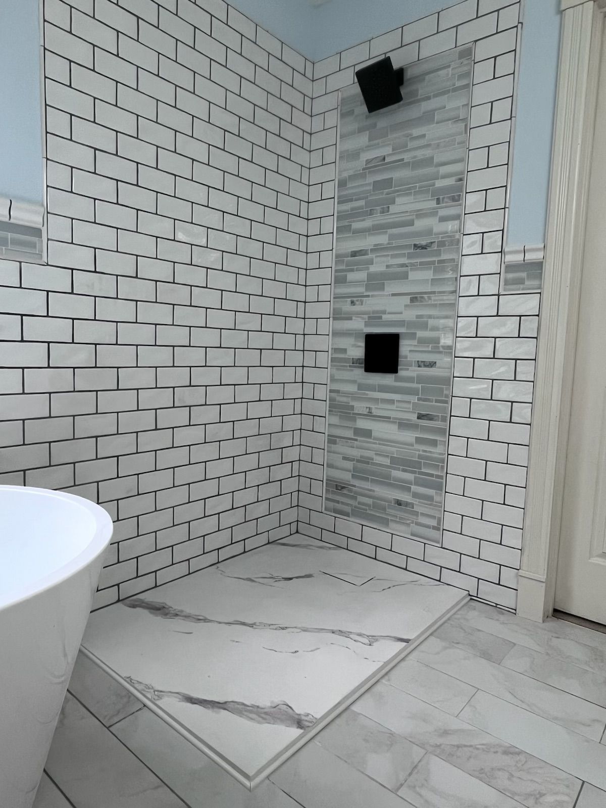 A bathroom with white brick walls and a walk in shower.