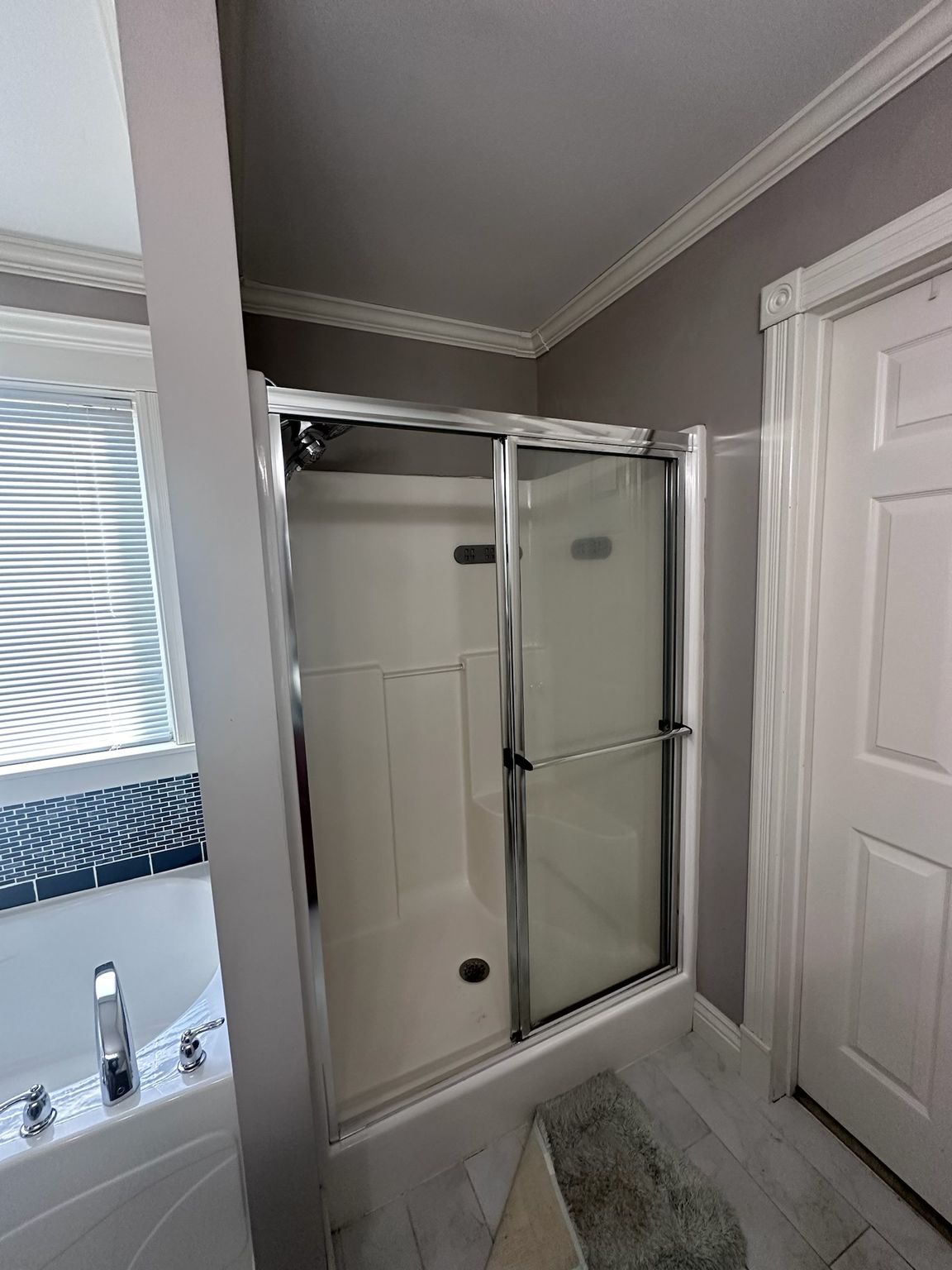 A bathroom with a walk in shower and a tub.