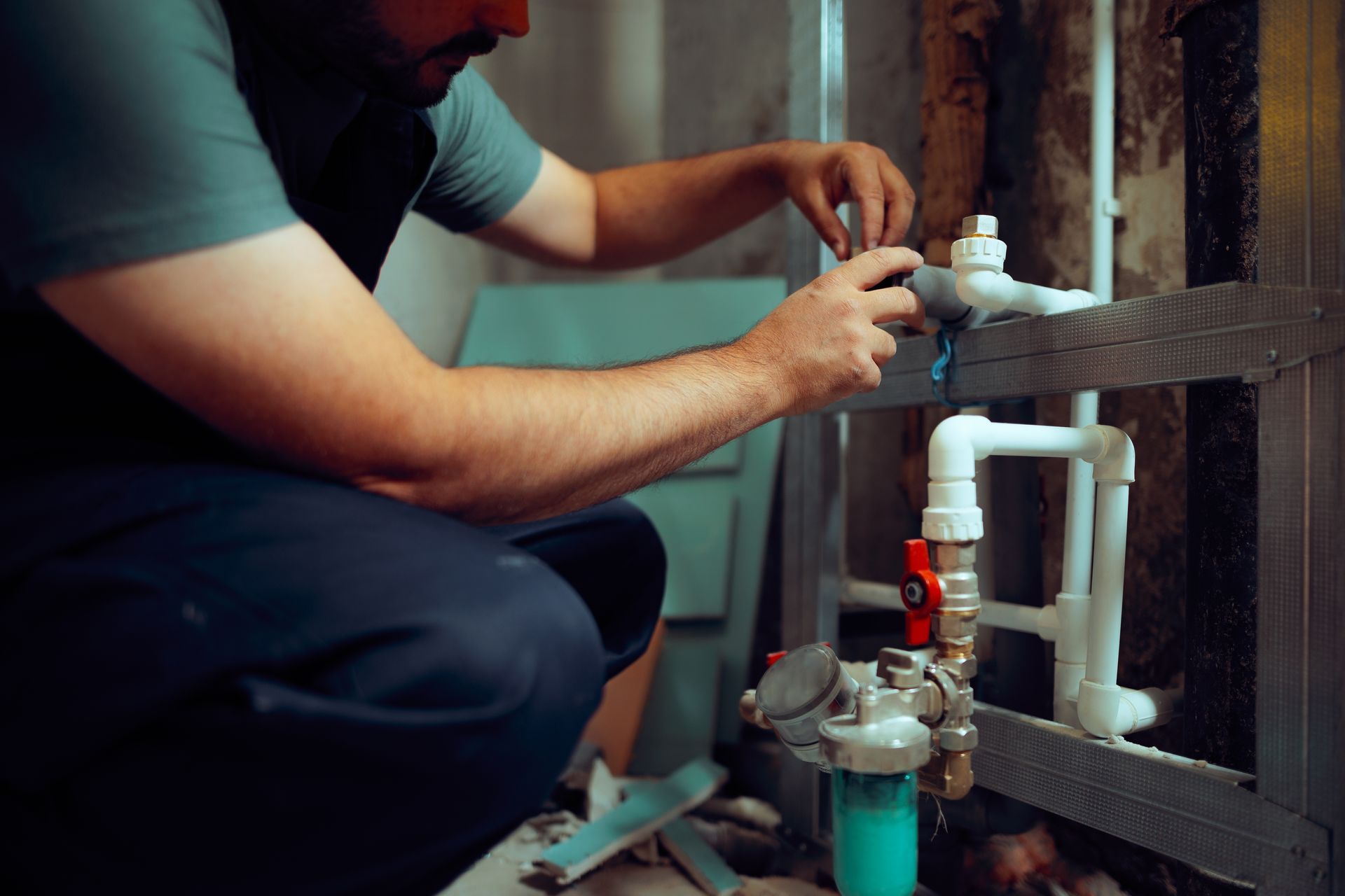 Plumber working on water pipes in a basement.