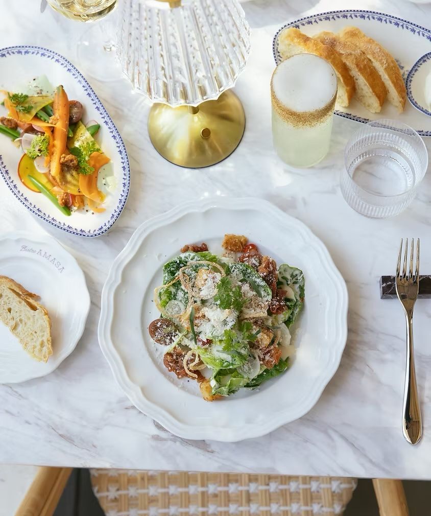 Elegant table setting with a fresh salad, bread, drink, and dessert on white dishes