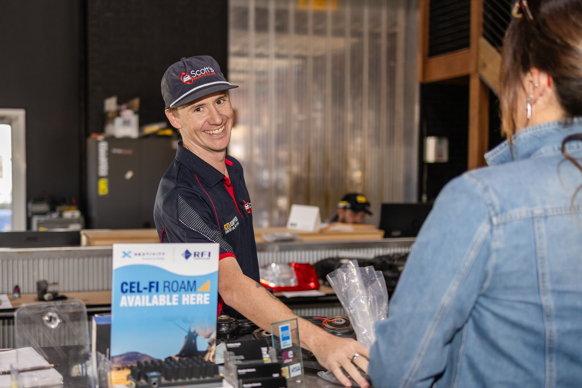 A Man at a counter serving a client — Scott's 4WD Parts Plus In Dubbo, NSW