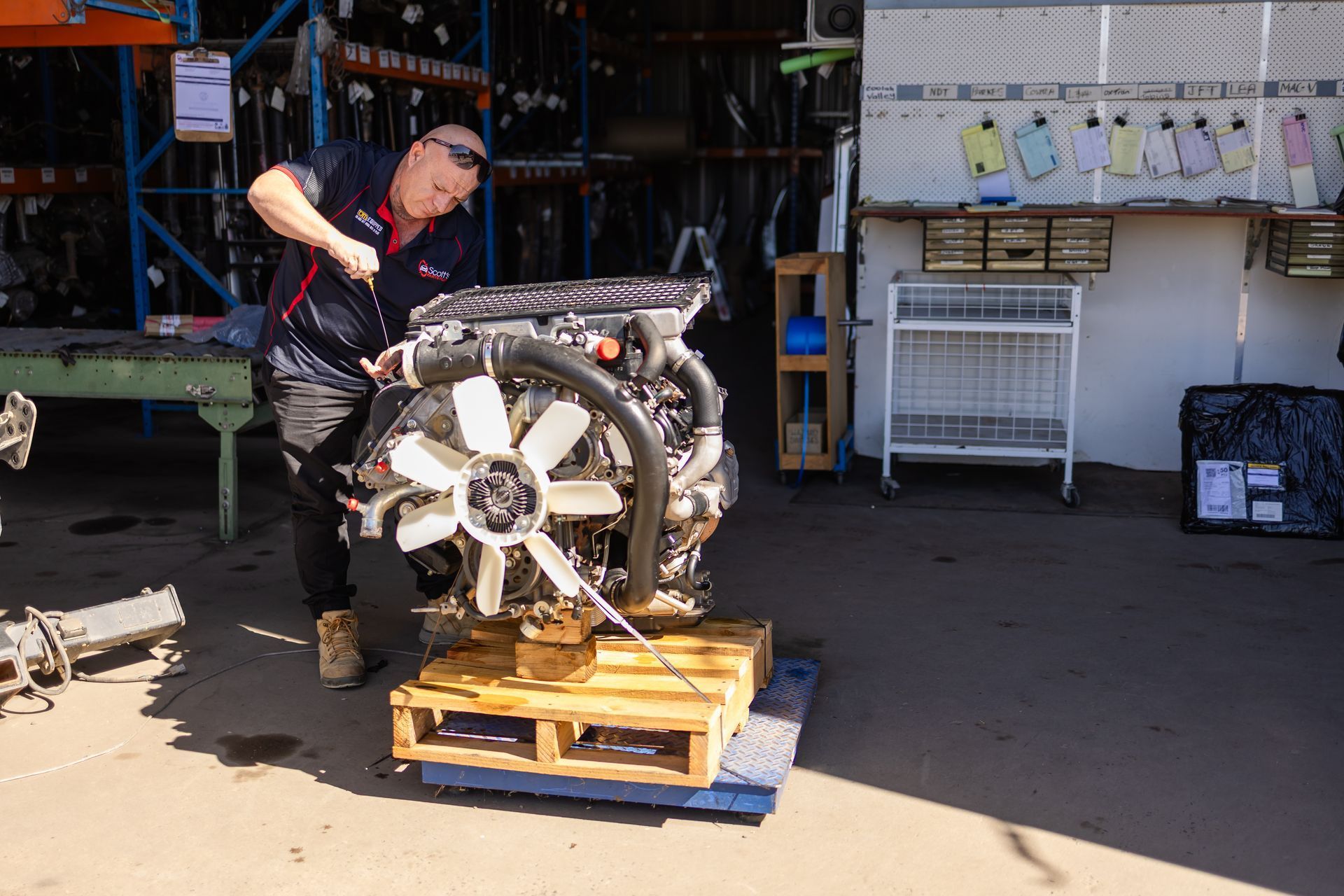 A man is working on a large engine — Scott's 4WD Parts Plus In Dubbo, NSW