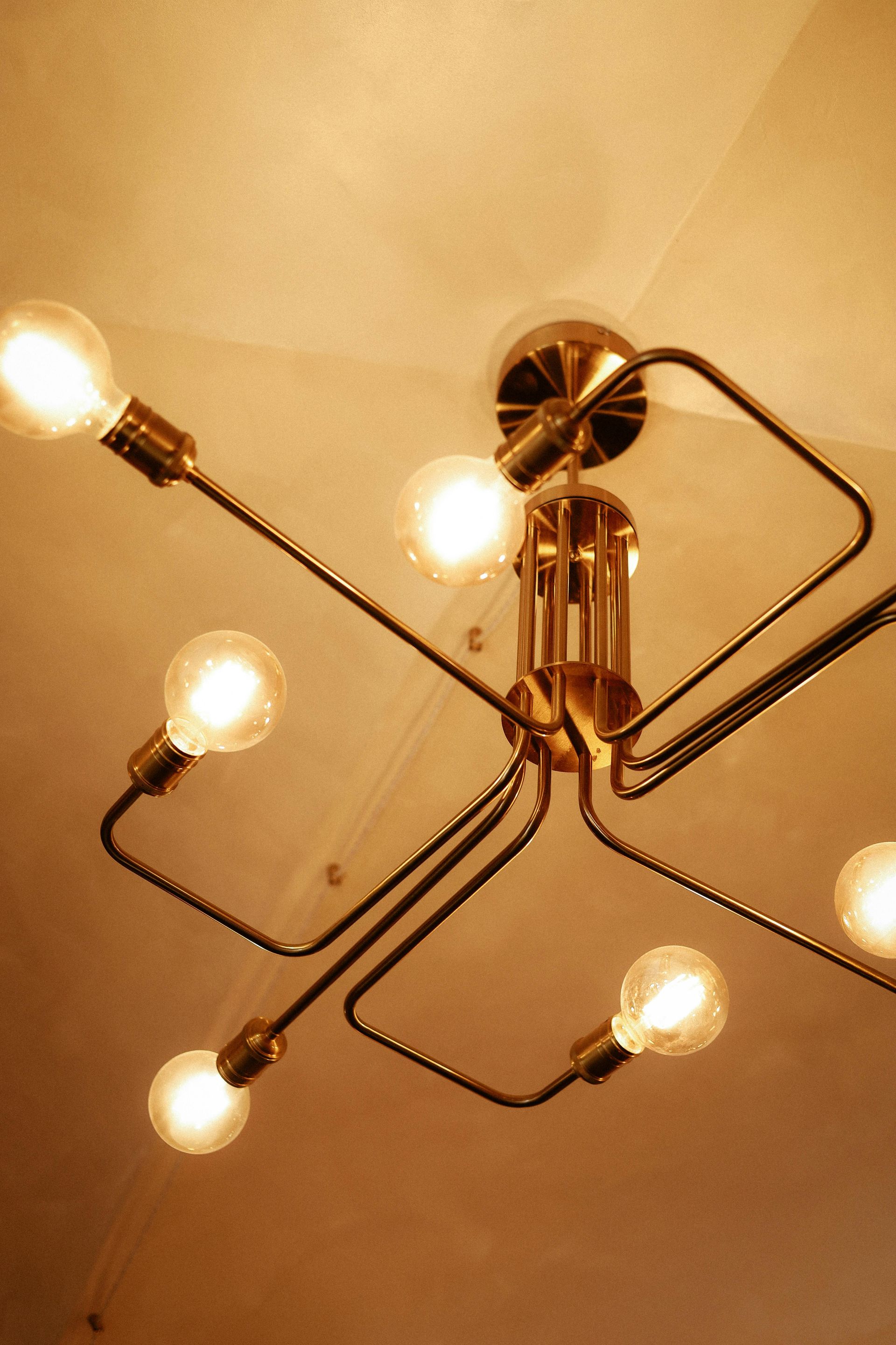 Modern ceiling light fixture with five glowing bulbs on a warm beige ceiling