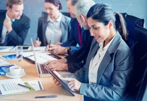 Colleagues in business attire reviewing documents and a tablet during a meeting at a conference table