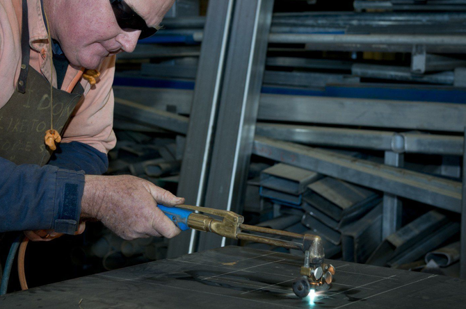 A man is welding a piece of metal in a factory.