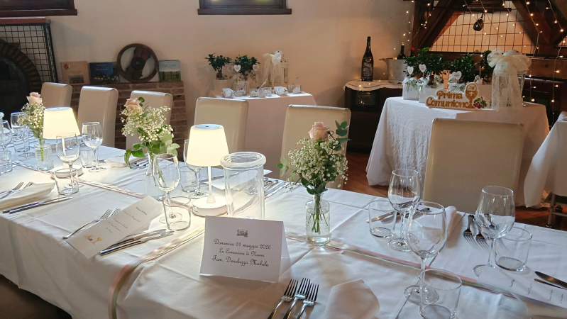 Elegante allestimento per la sala da pranzo, ideale per un evento formale, con tovaglie bianche, candele, fiori e posate.