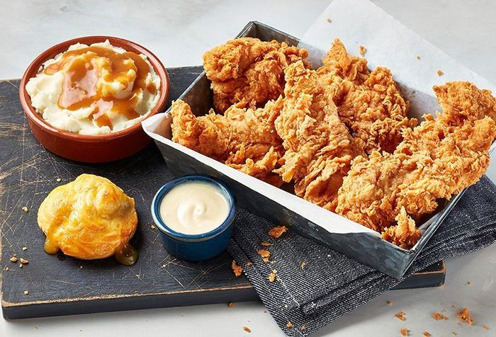There is a bowl of mashed potatoes and a bowl of fried chicken on the table.