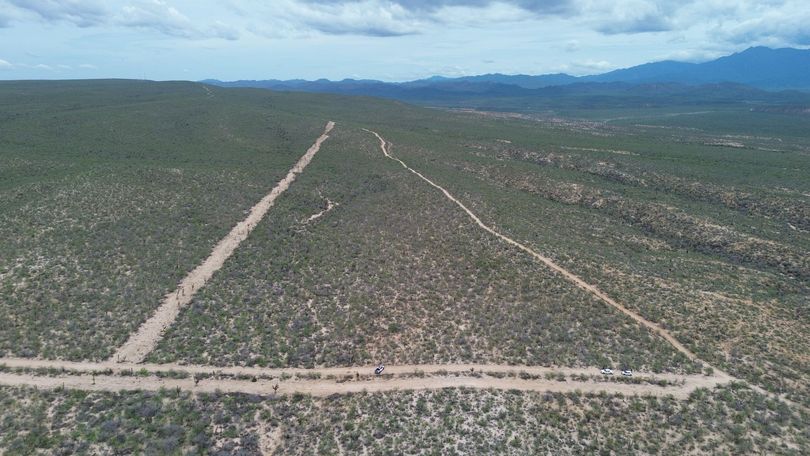 Aerial view of a wide, dirt trail forming a triangle shape through a desert landscape with sparse vegetation.