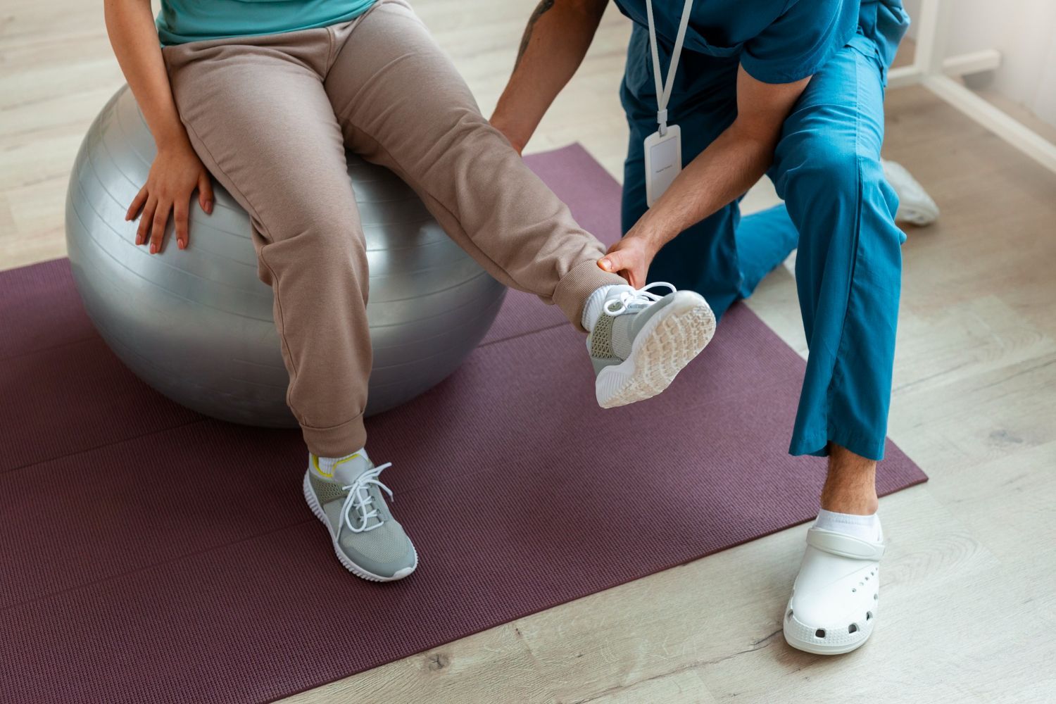 Physical therapist assisting leg exercise on an exercise ball in a clinic
