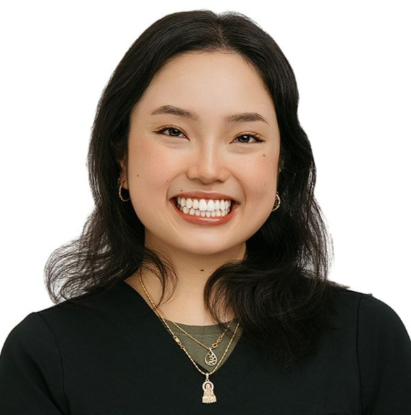 Smiling person with dark hair, black top, and layered gold necklaces against a white background